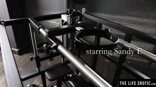 Kinky blonde Sandy E fingers her twat in a BDSM cage